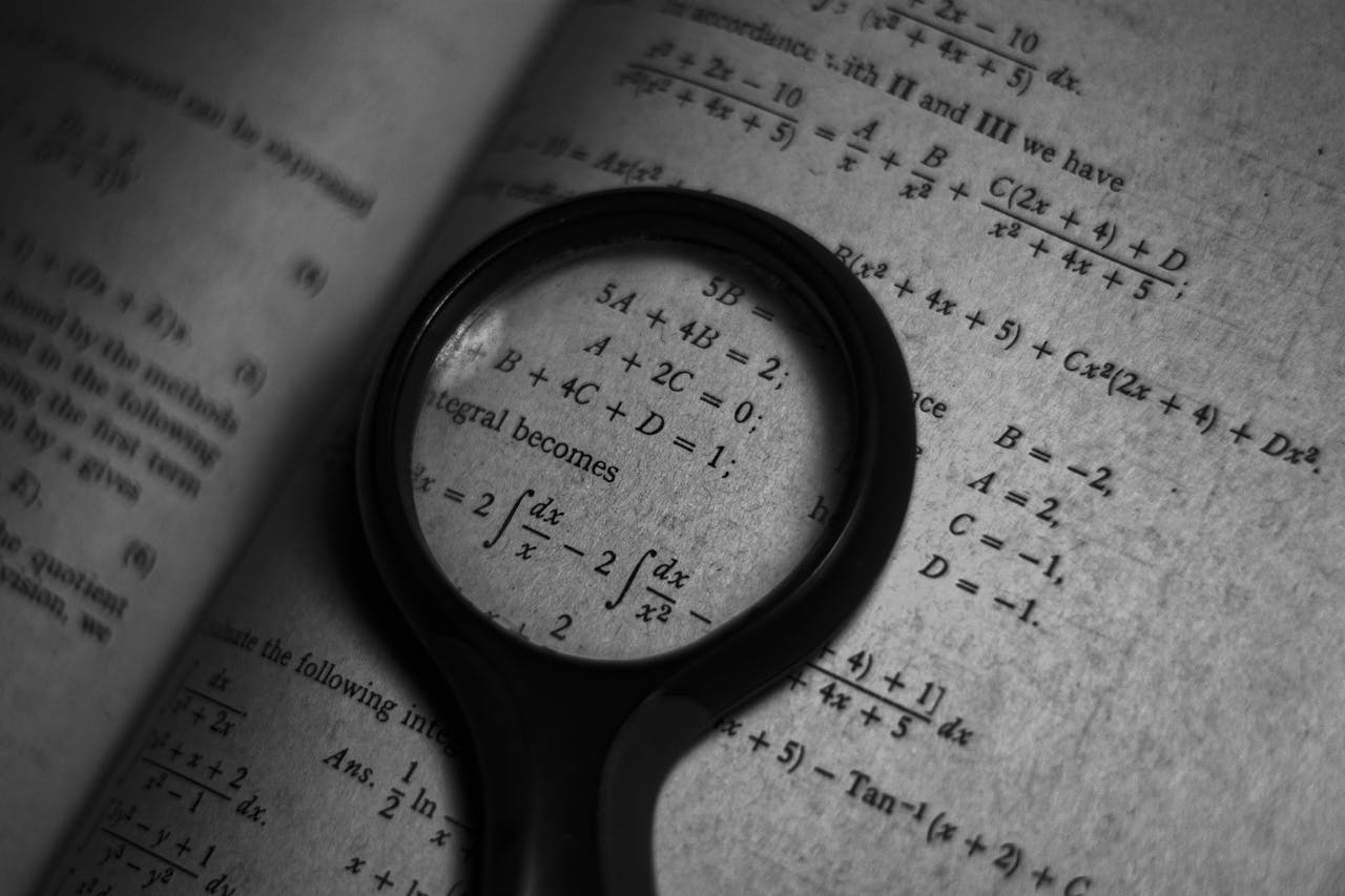 Mastering the First Impression: Your intriguing post title goes here A magnifying glass focuses on mathematics formulas in a book, enhancing study and exploration.