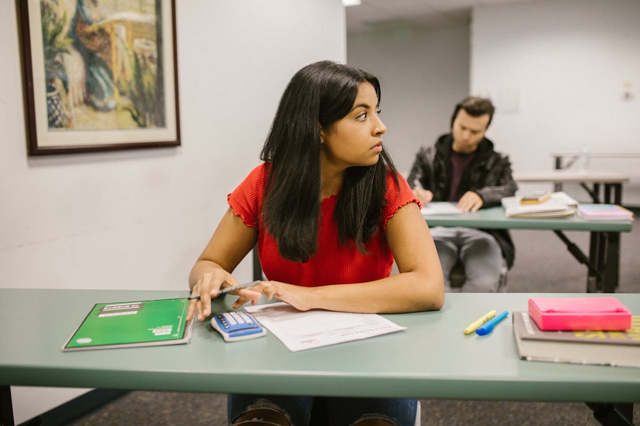 The Art of Drawing Readers In: Your attractive post title goes here Students taking a test in a classroom, with one woman looking sideways. Education theme.